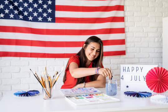 Beautiful woman drawing a watercolor illustration for Independence day of the USA, selective focus, focus on foreground
