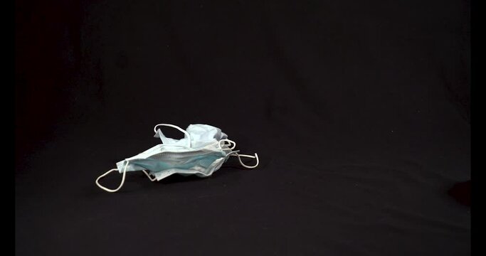 Used anti-covid surgical masks are thrown away and stacked up on a black background, recycling problem