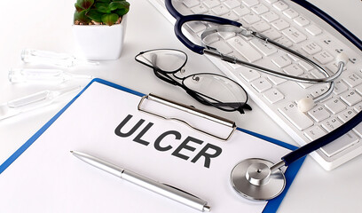 ULCER text on white paper on white background. stethoscope ,glasses and keyboard