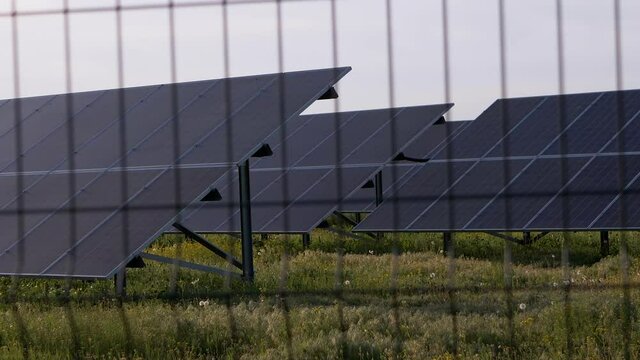 Solar Panels Fenced with Barbed Wire Fence. Solar batteries located on green grass by road, in a protected area behind a wire fence. Electricity generation. Restricted area. Lattice. Zoom. Close up