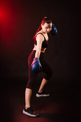Fototapeta na wymiar Sport woman boxer wearing blue boxing gloves on dark background