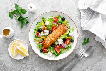 Salmon fish salad. Fresh vegetable greek salad with tomato, pepper, lettuce, olives, cucumbers, feta cheese and grilled salmon fish fillet, healthy food, omega 3, keto diet, mediterranean cusine