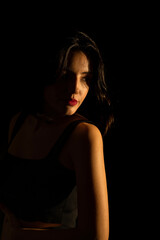 Fototapeta premium Portrait of attractive a young woman with cinematic lighting. Woman wearing a suspender bodysuit. Half naked sexy woman. Vertical shot.