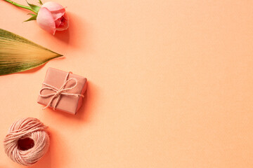 Gift box, string, rose flower on orange background. flat lay, top view, copy space