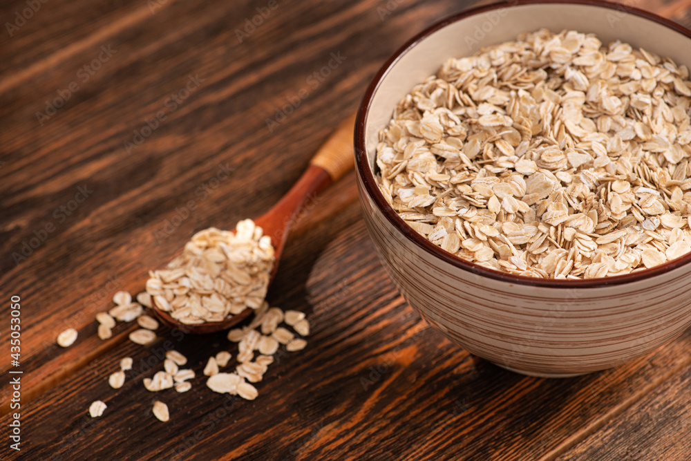 Wall mural Bowl with oatmeal flakes on a wooden background