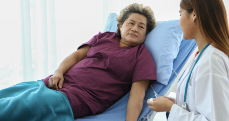 Obraz premium The doctor is using the syringe for the sick old woman lying on the bed