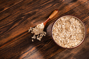 Obraz na płótnie Canvas Bowl with oatmeal flakes on a wooden background