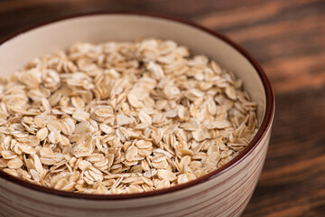 Bowl with oatmeal flakes on a wooden background