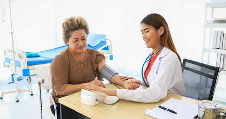 The Doctor using blood pressure gauge for checking to old women patients in his office at Hospitals