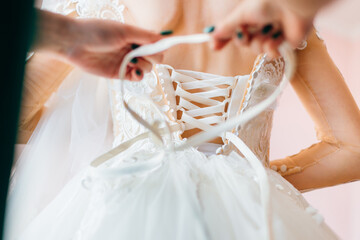 The bridesmaid prepares the bride for the wedding day, helps to button and tie her dress....