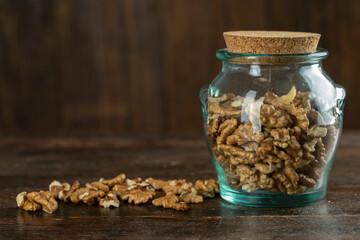 Peeled walnuts in a glass jar on a wooden table.