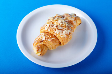 Plate with tasty croissant on blue background.