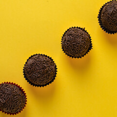 Traditional brazilian chocolate candy called "Brigadeiro" on yellow background.