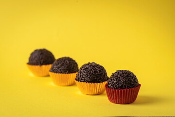 Traditional brazilian chocolate candy called "Brigadeiro" on yellow background.