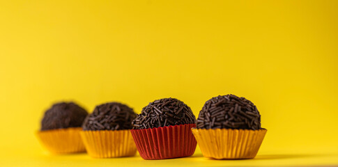Traditional brazilian chocolate candy called "Brigadeiro" on yellow background.