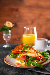  Croissants with arugula, avocado and salmon, a cup of black coffee and a glass of orange juice on the table, breakfast concept with soft focus vertical photo