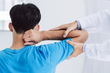 Professional physiotherapists provide assistance to male patients with arm injuries examine...