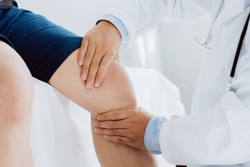 Doctor physiotherapist working examining treating injured knee of patient, his using the handle to the patient knee to check for pain. - obrazy, fototapety, plakaty