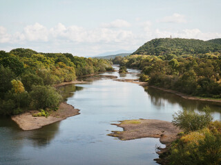 Fototapeta na wymiar The Ussuri river in summer between green trees on the way from Khabarovsk to Vladivostok