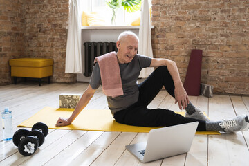 Elderly man watching online fitness class during his home workout