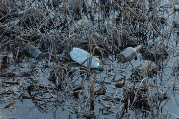 plastic bottles, glass bottles and cans on the shore of the reservoir. Environmental pollution concept, ecology.