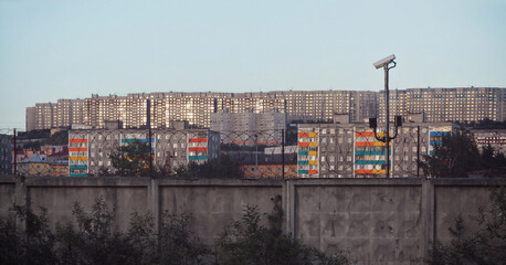 Concrete fence with barbed wire and a view of high-rise buildings in the city of Murmansk