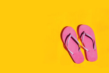 Pink flip flops on bright yellow background. Copy space.