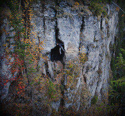 Obraz na płótnie Canvas A man climbs the rocks in the autumn forest of the Perm Territory on the Usvensky pillars