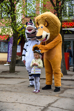 Russia, Gatchina, May 15, 2021: A man in a lion and zebra costume on a city street embraces and takes photos with passers-by. Advertising on the street. Work in advertising.