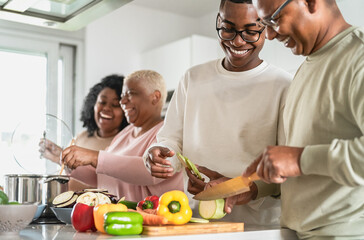 Happy African family having fun in modern kitchen preparing food recipe with fresh vegetables - Food and parents unity concept