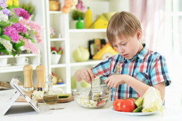 Obraz na płótnie Canvas boy preparing delicious fresh salad in kitchen