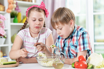 Cute brother and sister eating  together in kitchen
