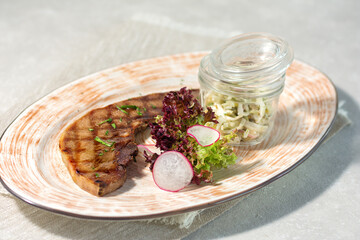 grilled tongue, served on a platter with lettuce and radishes and a serving of lettuce in a separate transparent bowl. Summer menu concept