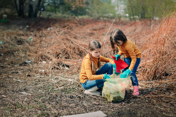 Two children are cleaning in the park, Children with garbage bags pick up garbage in the forest....