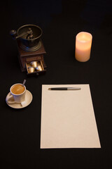 Feuille blanche avec stylo et tasse de café près du moulin à café et éclairé à la bougie et reflet bleu