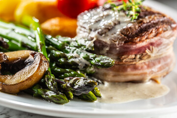 Grilled steak served on a plate with asparagus, potatoes and mushroom sauce