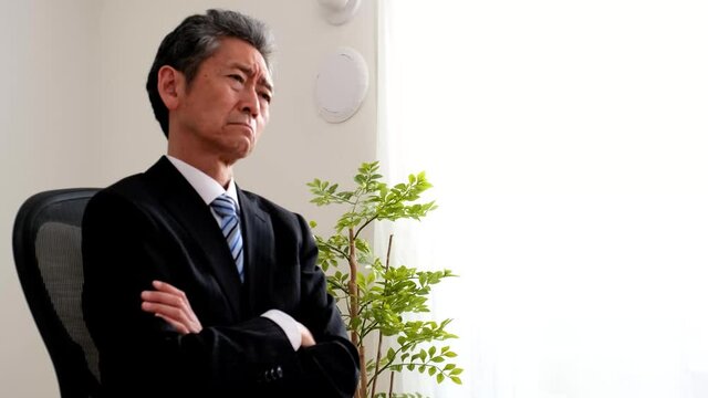 椅子に腰掛けて悩むシニア社長