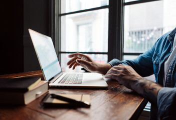 Close-up of male hands with laptop. Man is working remotely at home. Freelancer at work