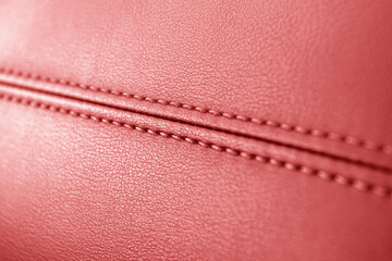 Modern luxury car red leather interior. Part of perforated leather car seat details. Red perforated leather texture background. Texture, artificial leather with stitching. Leather dashboard