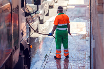 Street cleaning service worker washing asphalt with special equipment