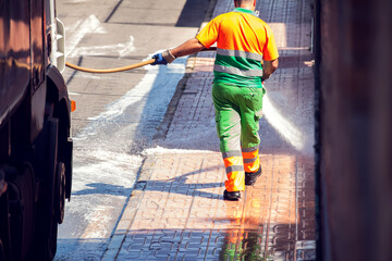 Street cleaning service worker washing asphalt with special equipment