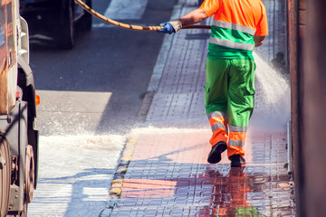 Obraz na płótnie Canvas Street cleaning service worker washing asphalt with special equipment