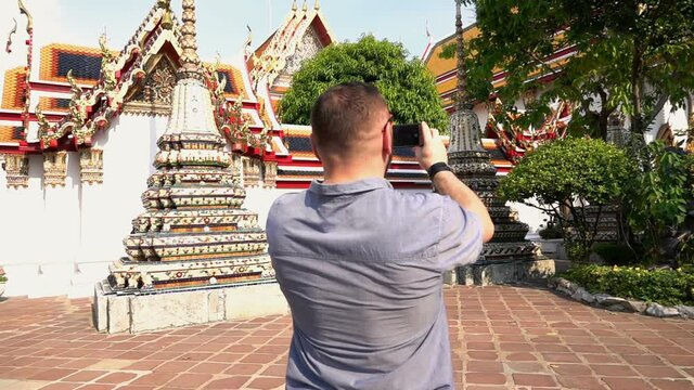 Man taking photo of beautiful Buddhist temple in Bangkok, slow motion