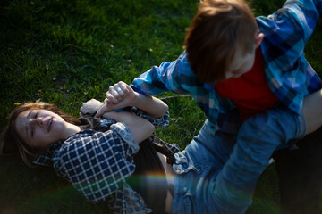 Boy and girl teenagers are fighting on the grass in nature