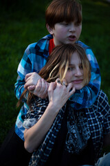 Boy and girl teenagers are fighting on the grass in nature