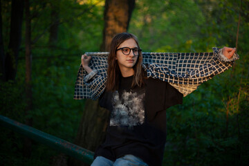 Teenage girl in glasses in a cardigan shirt in nature