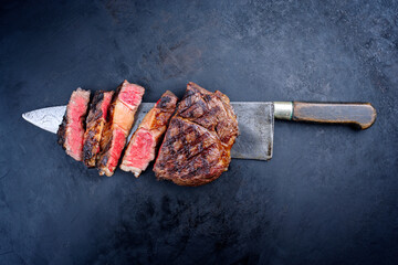 Traditional barbecue dry aged wagyu rib-eye beef steaks sliced and served as top view on a rustic...