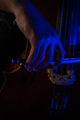 Artistic photo of a young man playing the cello where you can see the detail of the hand with the bow rubbing the strings.