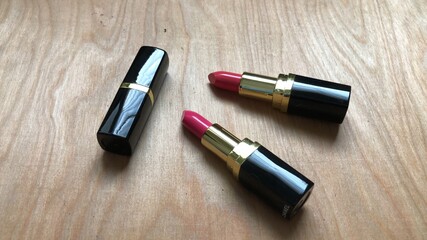 Obraz premium Red matte lipstick on wood background,with natural dimly light,free space for your text design,selective focus.