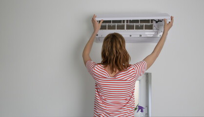 Woman repairing air conditioner at home. - obrazy, fototapety, plakaty
